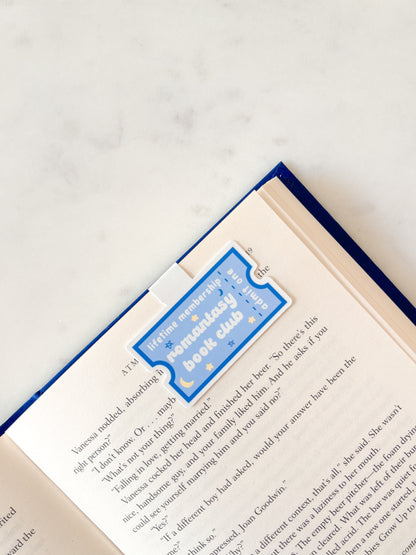 Open book with a blue bookmark on a white surface